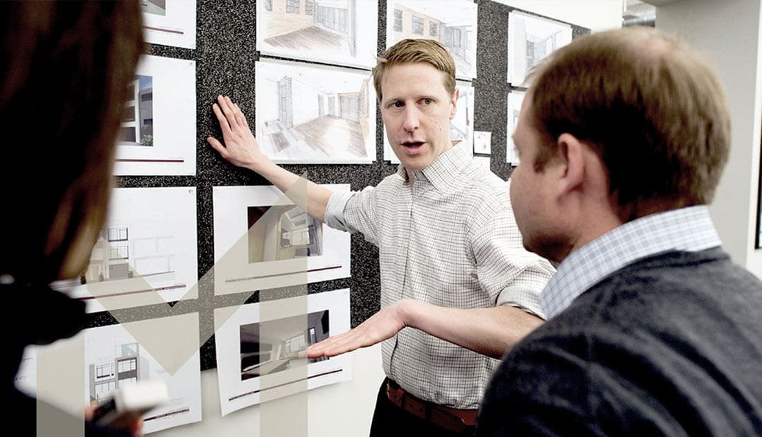 two men discussing images posted on a wall