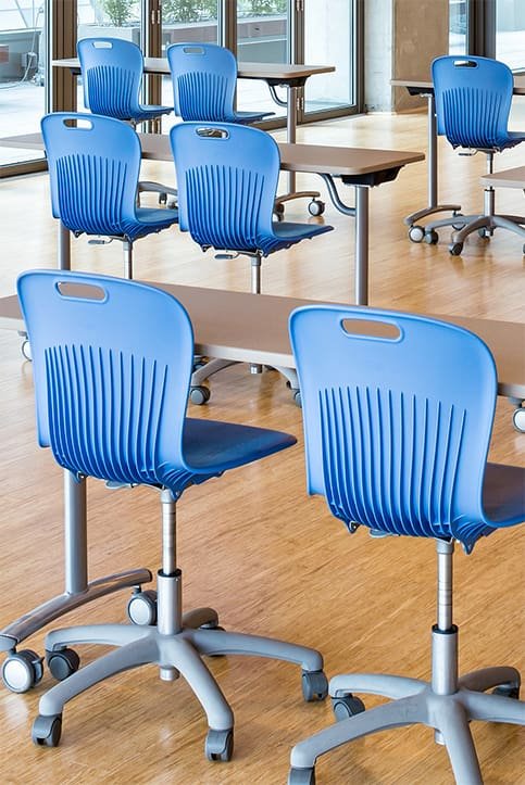 blue chairs with wheels in a classroom with brown desks